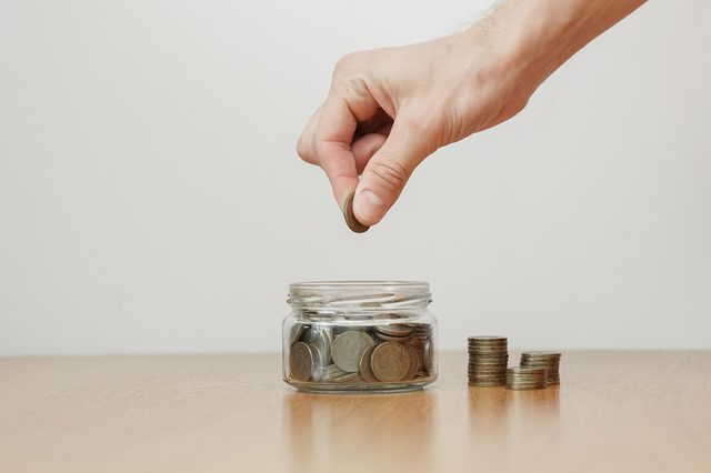 Hand putting money coin in to the glass jar. Future investment, good profit