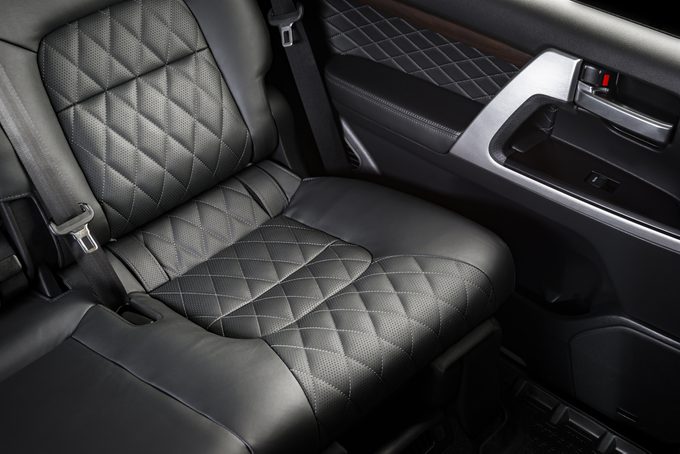 Back passenger seats in modern luxury car, frontal view, perforated black leather with stitching