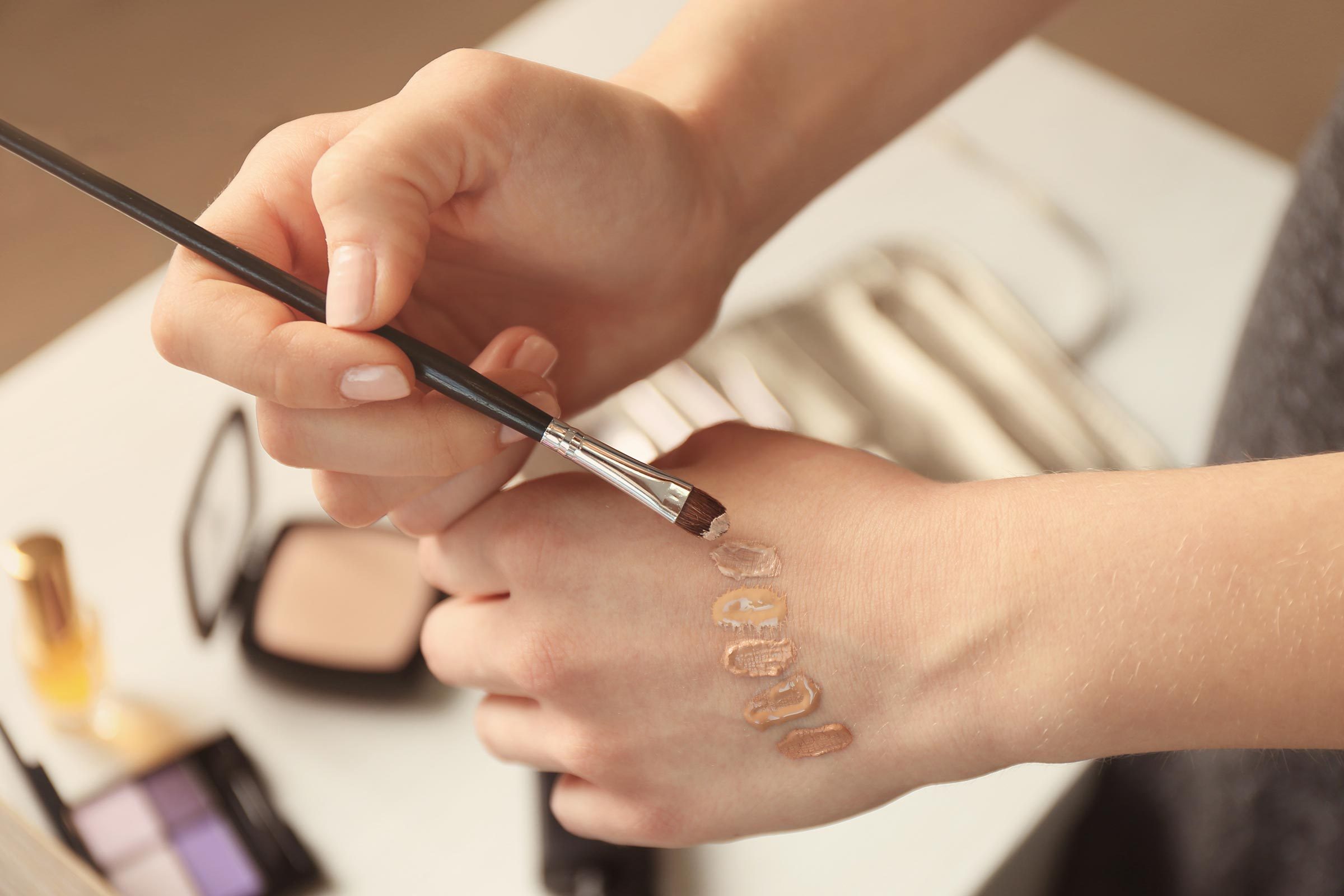 a woman brushing foundation colors onto the back of her hand