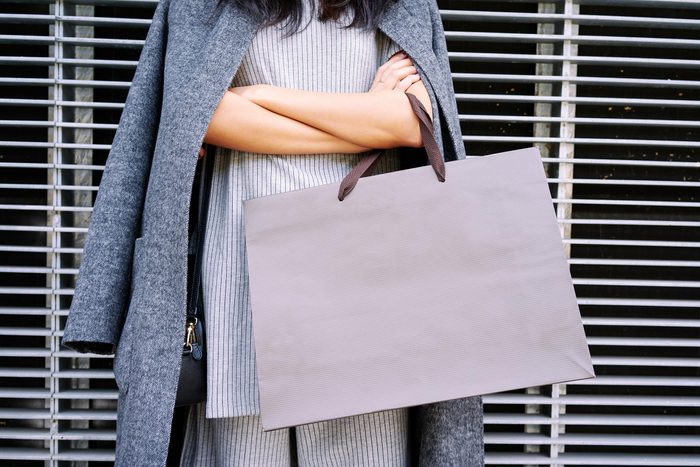woman with arms crossed holding a shopping bag