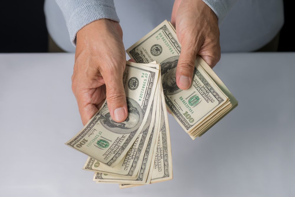 Man hand holding money,bribery concept. Business man giving stack of US dollar.