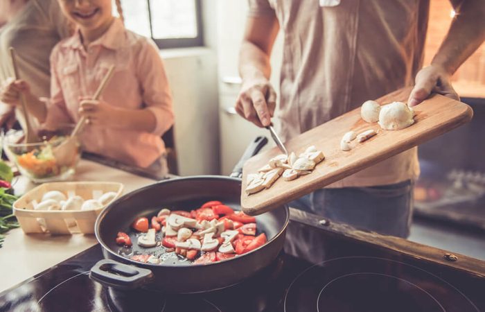 Cropped image of cute little girl and her beautiful parents cooking together in kitchen at home