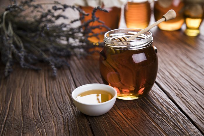Honey in jar with honey dipper on wooden background