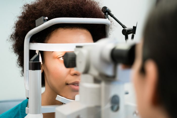 Woman having eyes measured with refractometer at optician or ophthalmologist