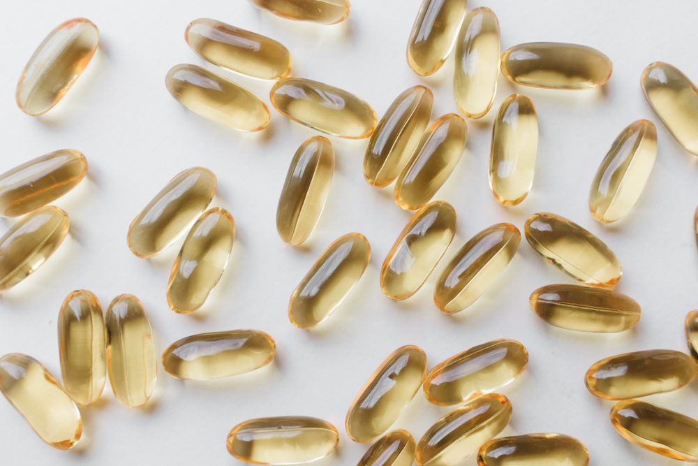 Pile of scattered capsules with medication on white background