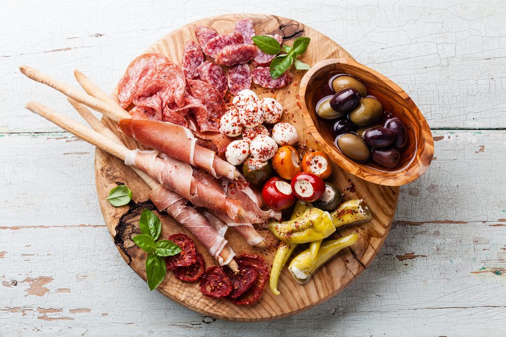 Cold meat plate and grissini bread sticks on wooden background