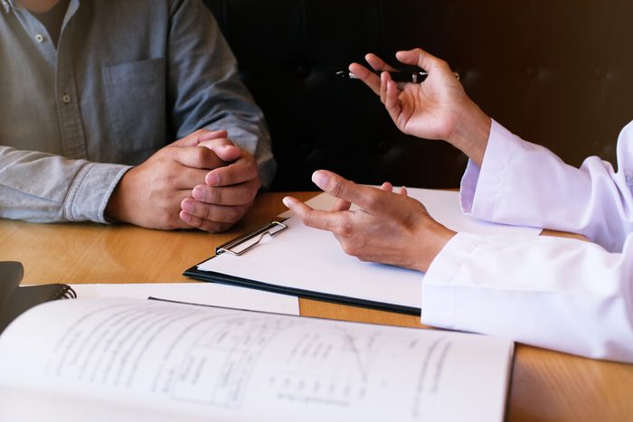 Professional medical doctor in white uniform gown coat interview consulting patient.