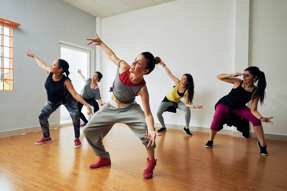 Group of energetic hip-hop dancers focused on training while gathered together in spacious dance hall