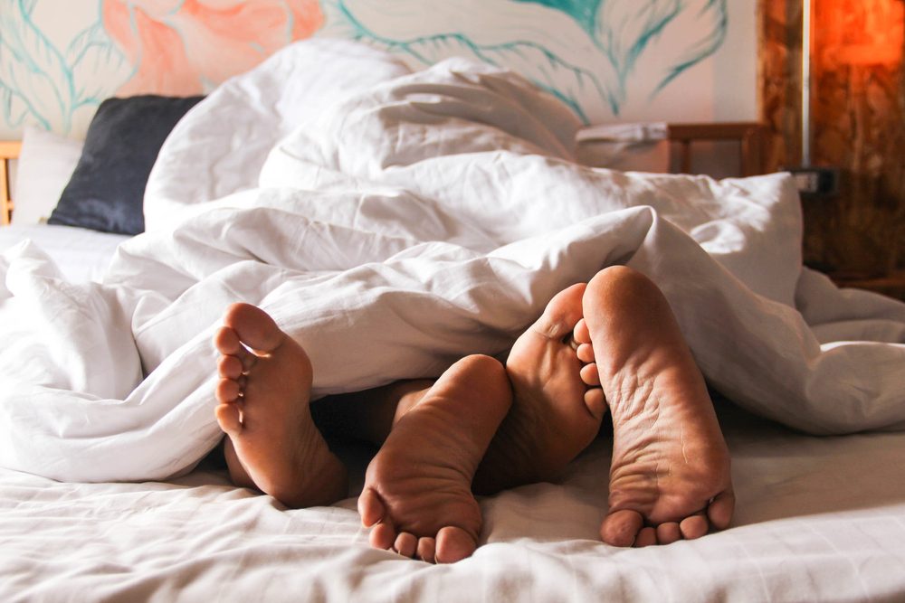 Passionate love. Feet of a young couple that lying on the bed at honeymoon. Couple in love having sex / Lovers having sex under blanket. Concept : love, sex, sweetheart, sweet, activity, lifestyle.