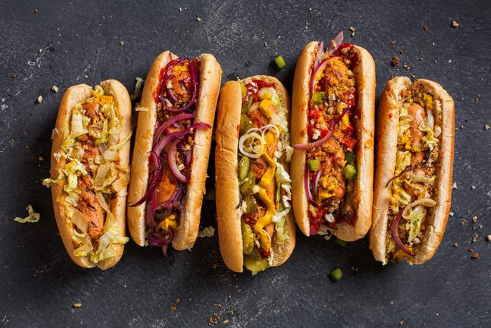 Hot dogs with a sausage on a fresh rolls garnished with mustard and ketchup and served with different toppings.