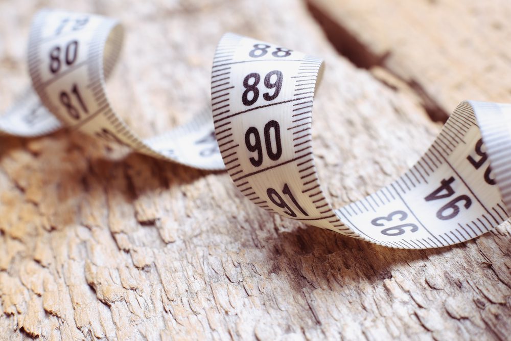 Centimeter on the table. Measuring tape on a table. Diet, weight loss, sports. The concept of slimness. Wellness. Measuring tape on old wooden table.