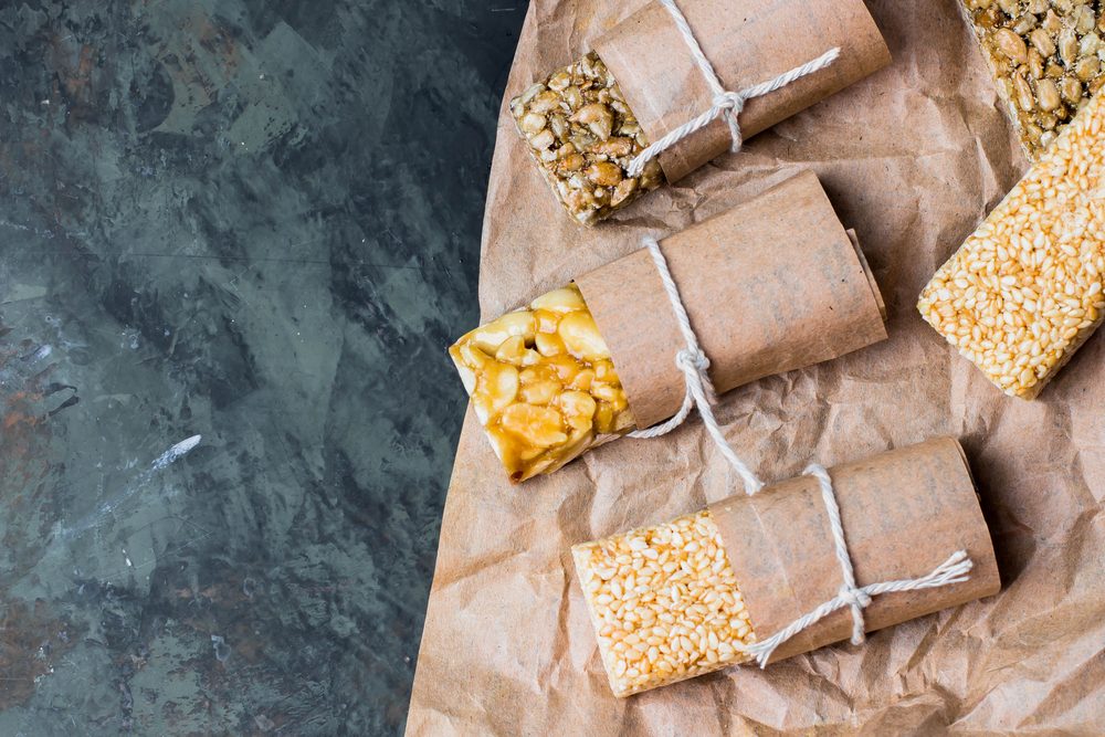 Nuts in caramel, honey on dark table background. Snack food. Unhealthy eating. Copy space