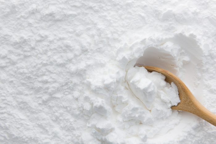 Close-up of tapioca starch or flour powder in wooden spoon with starch background