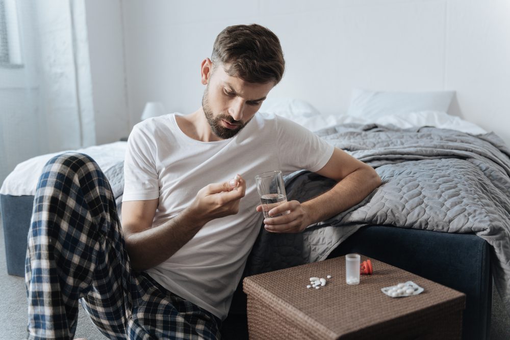 Sad unhappy man taking pills