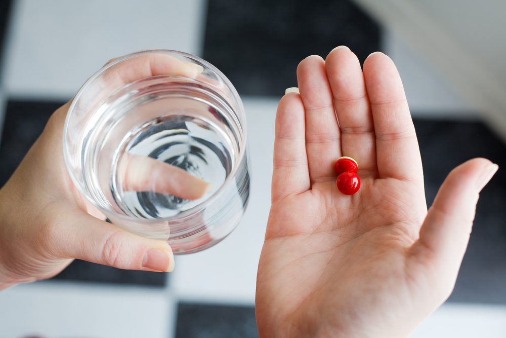 hand holding medicine and glass of water