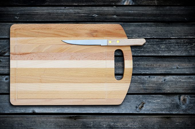 Empty bamboo cutting board and knife on a old wooden table for product display.Top view