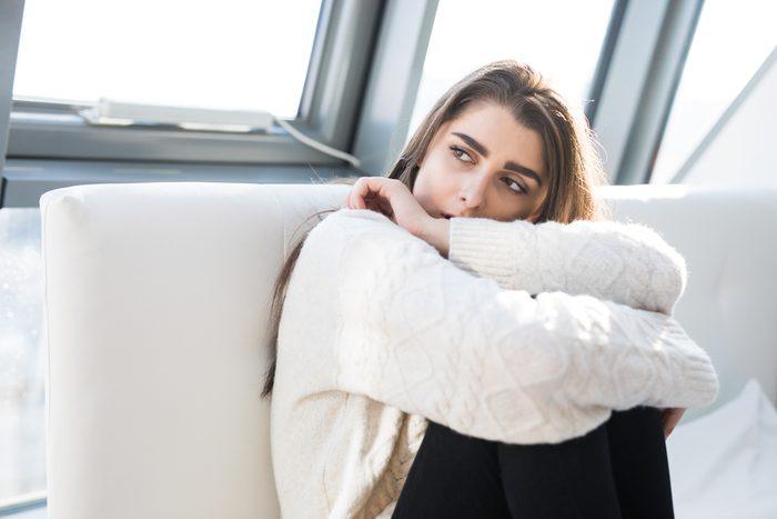 Thoughtful woman sitting on the bed at home