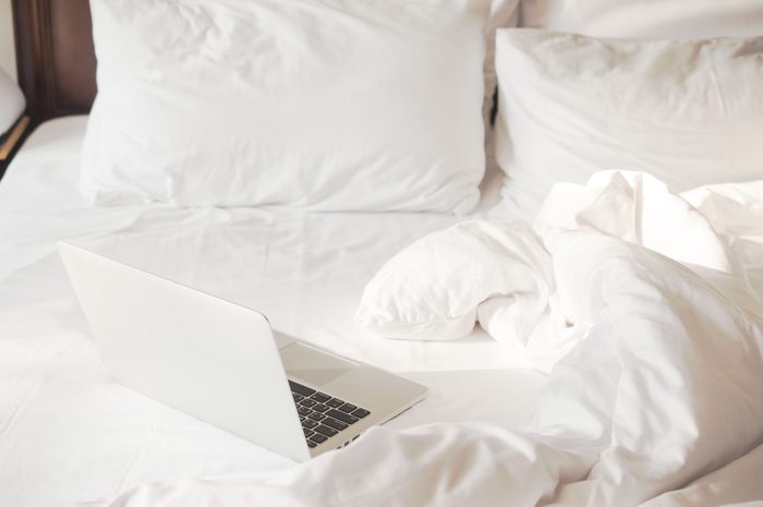 Laptop on white bed work at home concept