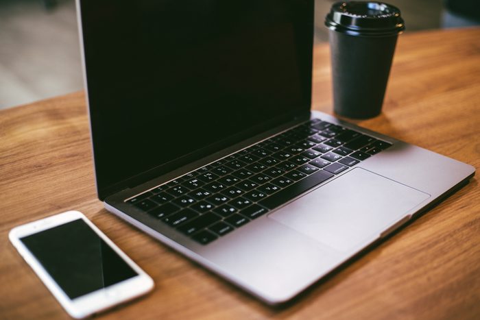 Laptop with phone and coffee stand on wooden table