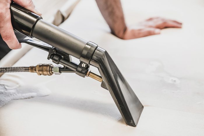 Cleaning couch with professional spray cleaner