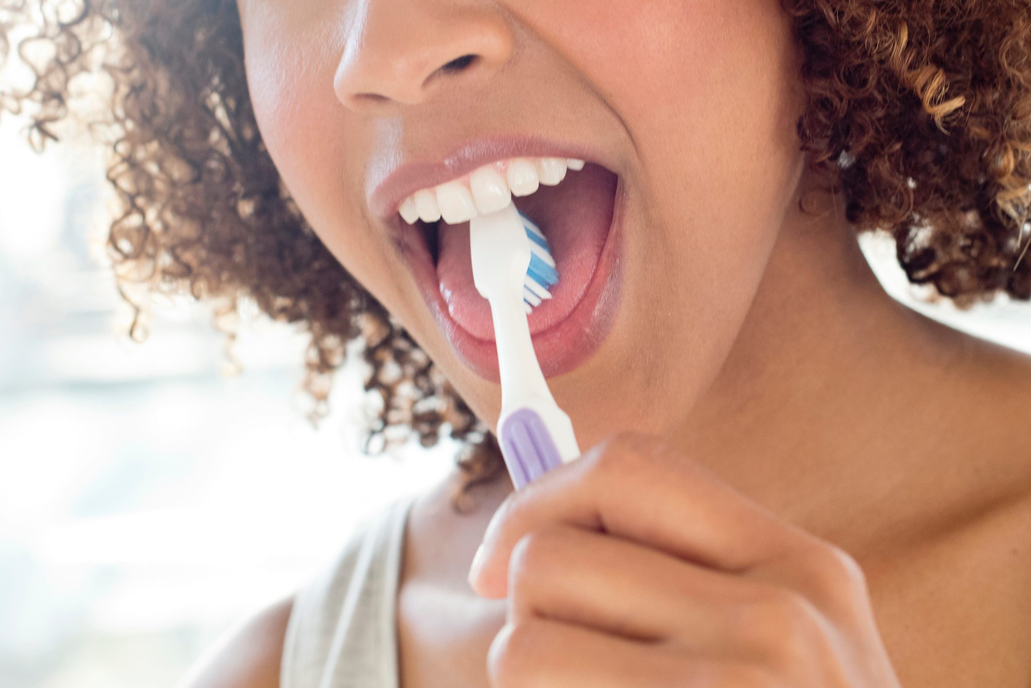 close up of woman brushing tongue