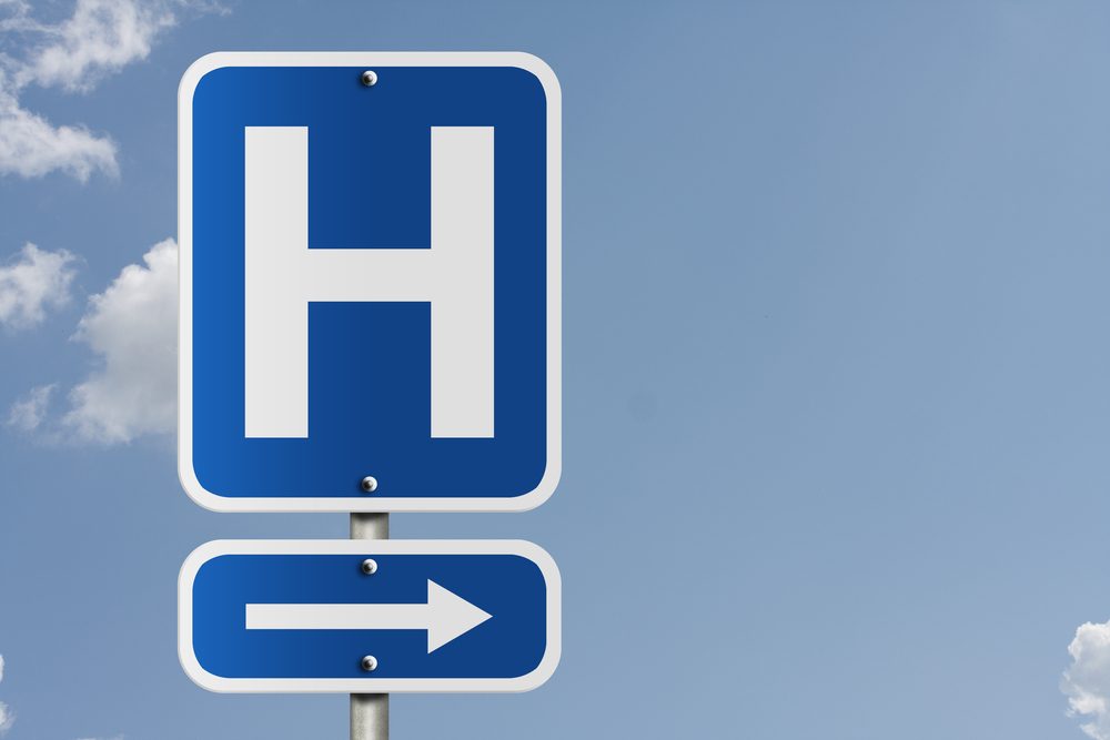 An American road sign with a sky background and a capital H, Hospital Direction Sign