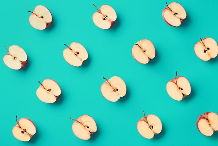 Colorful fruit pattern of fresh apple halves on blue background. From top view