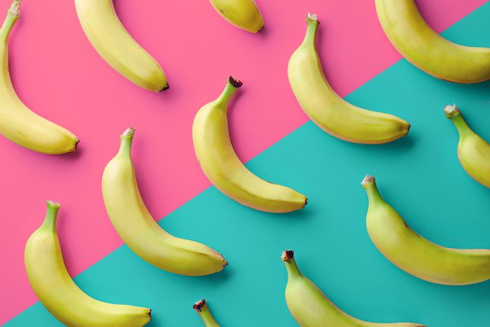 Colorful fruit pattern of fresh yellow bananas on pink and blue background. From top view