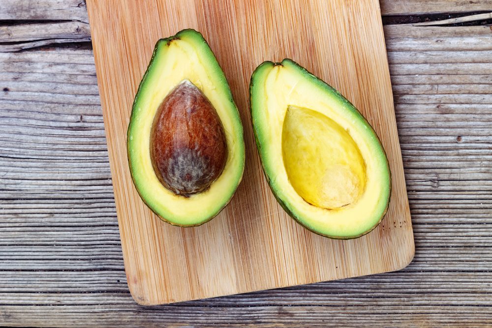 ripe avocado sliced in half on a cutting board