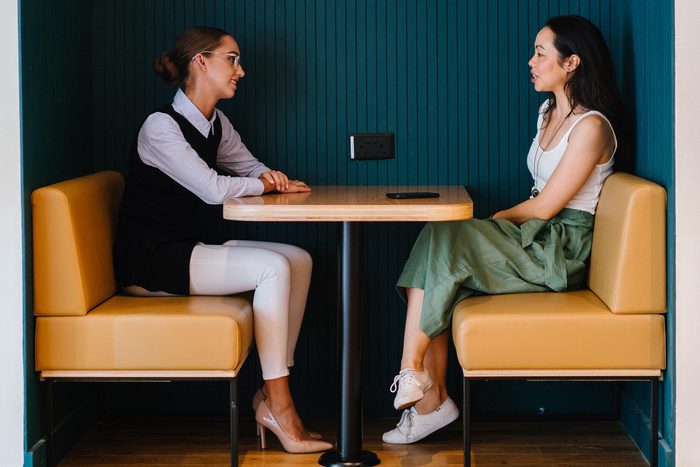 women sitting at table discussing talking