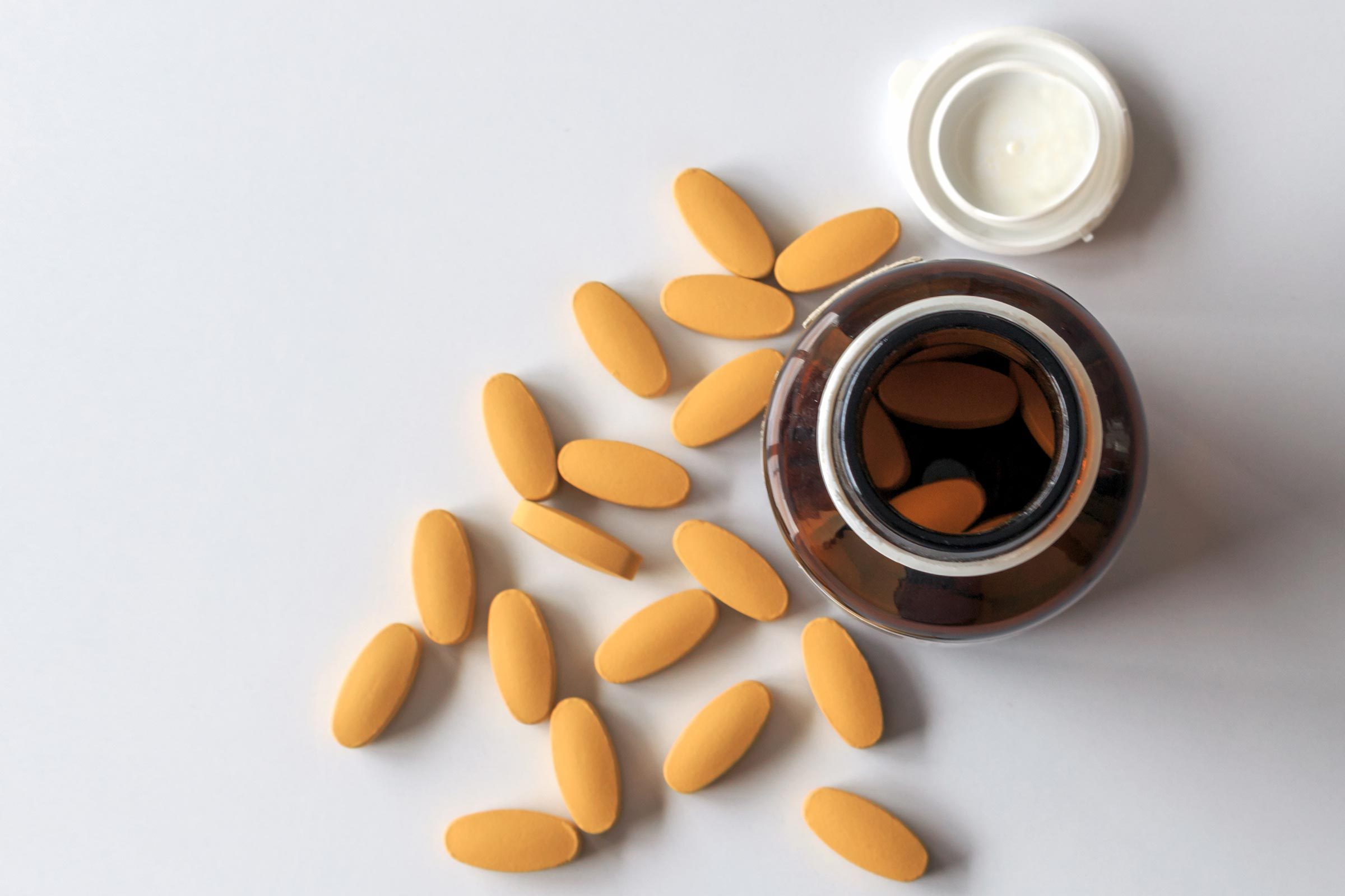supplements on a table next to an open pill bottle