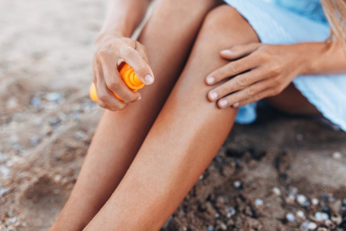 Beautiful girl, sun cream application, on the beach, feet close-up, jar of sun cream