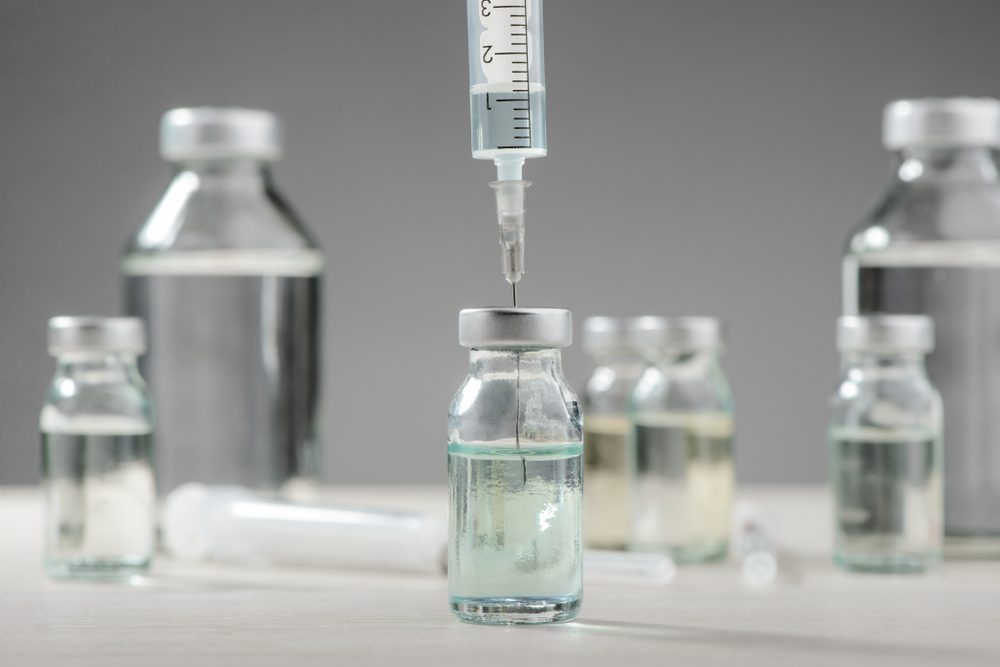 Drawing medication out of a vial, selective focus and blurred gray background. Healthcare, getting ready for injection.