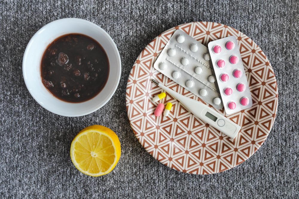 Thermometer, jam, lemon, tablets for colds on the grey background