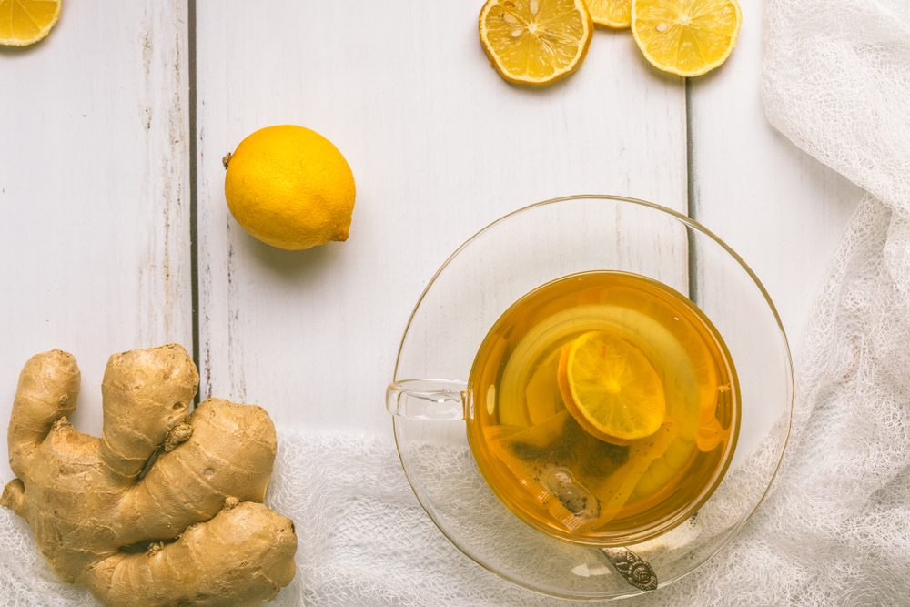 Healthy, organic green tea with sliced ginger and lemon, in a glass cup