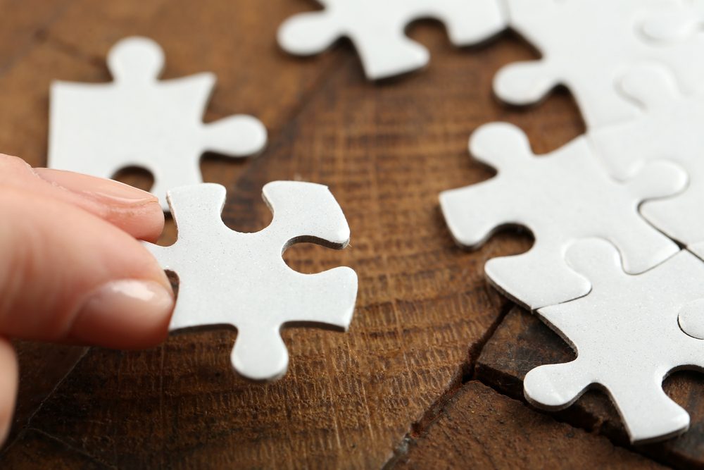 Woman playing with jigsaw puzzle on wooden table