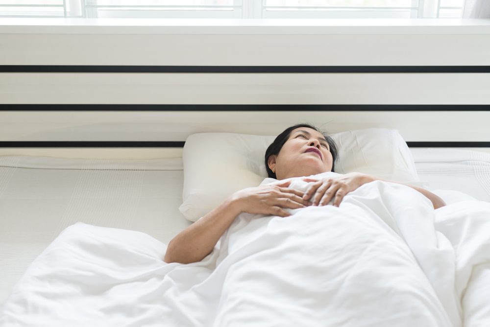 Elderly asian woman depressive have a headache and feeling consider seriously in bedroom