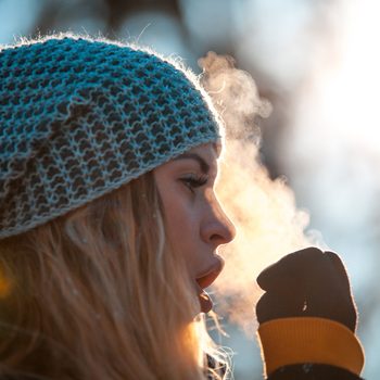 Woman breathing on her hands to keep them warm at cold winter day