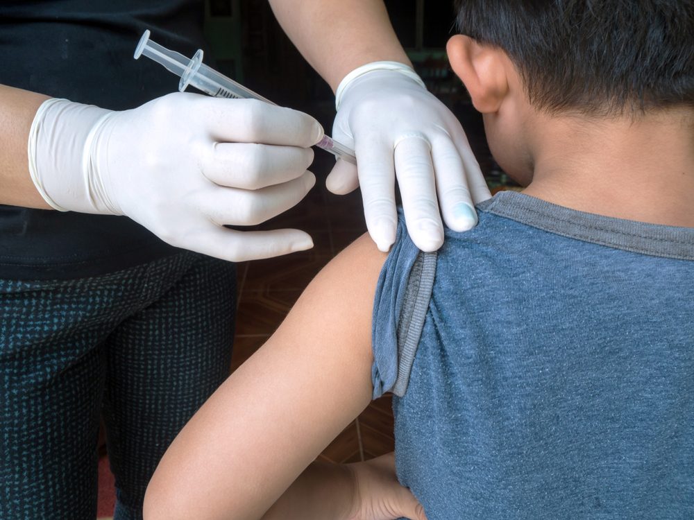 Doctor preparing an injection in the arm boy.