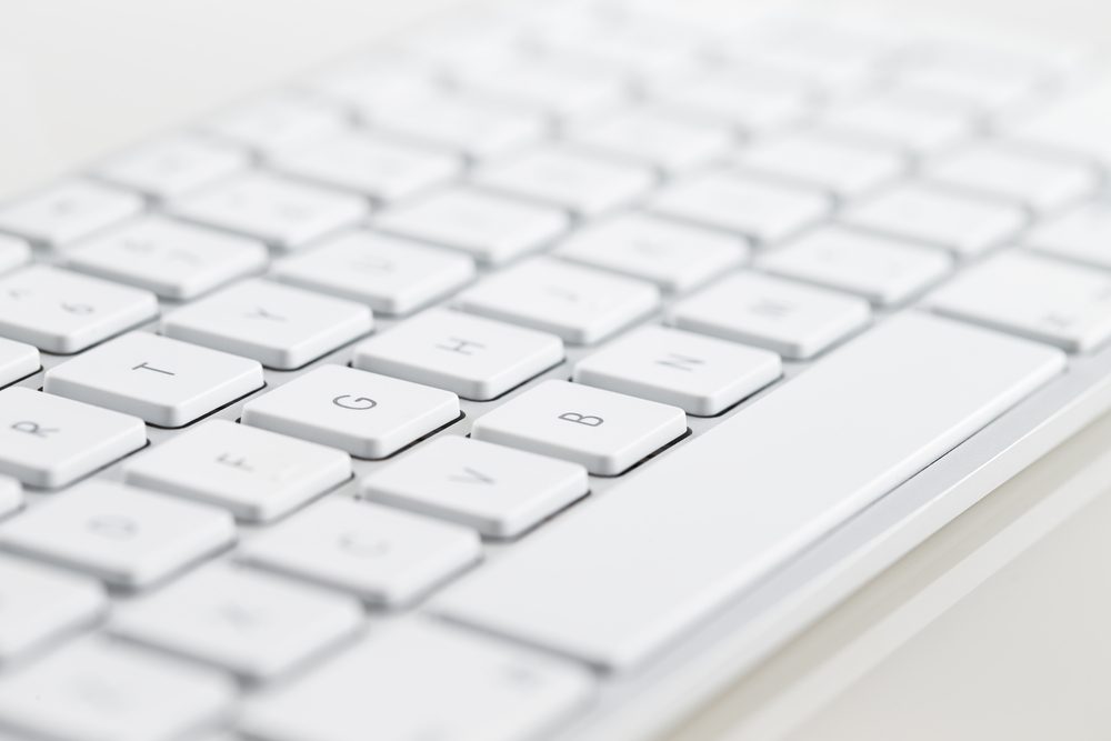 A close-up of a white computer keyboard on a white background