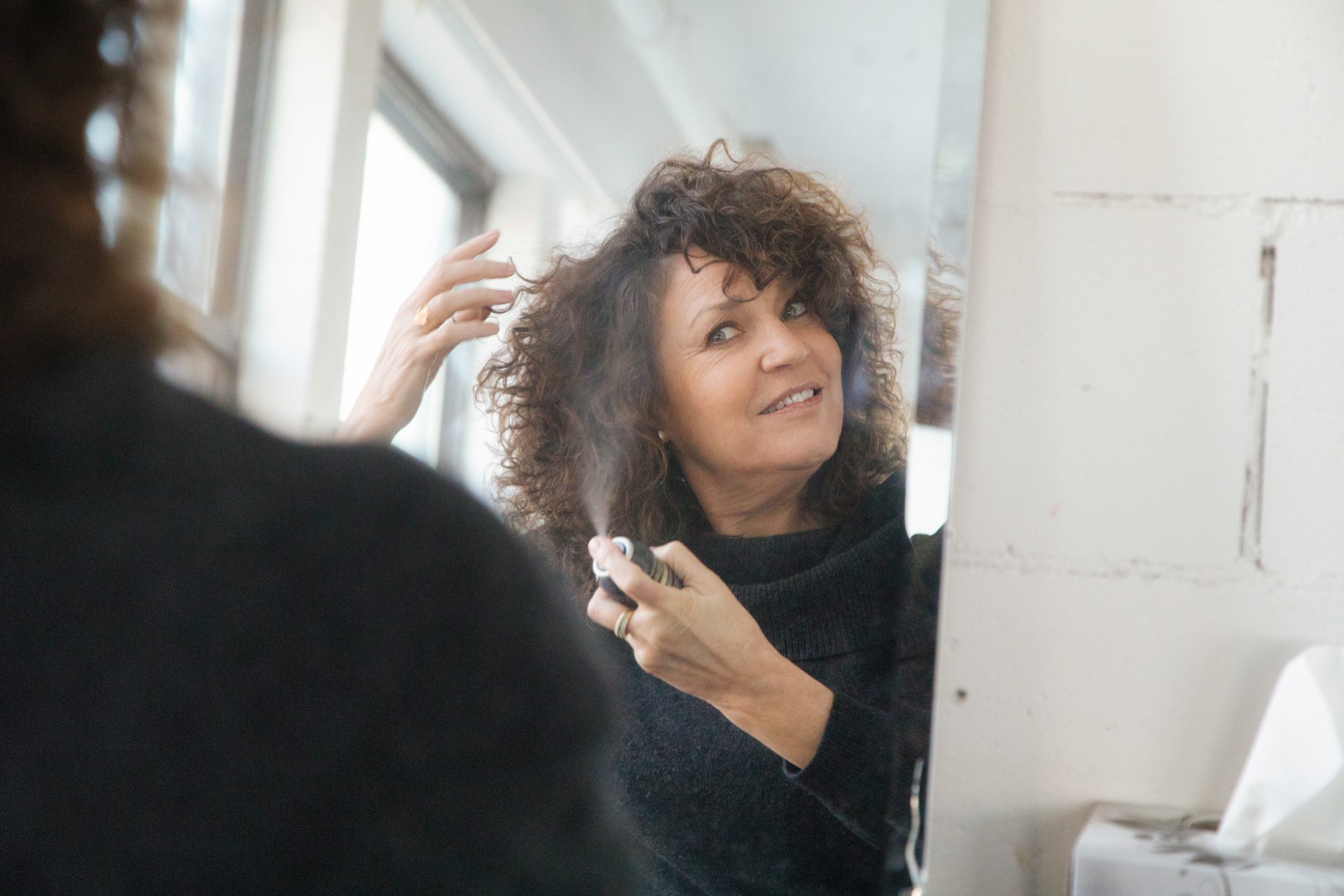 woman spraying hairspray into her hair