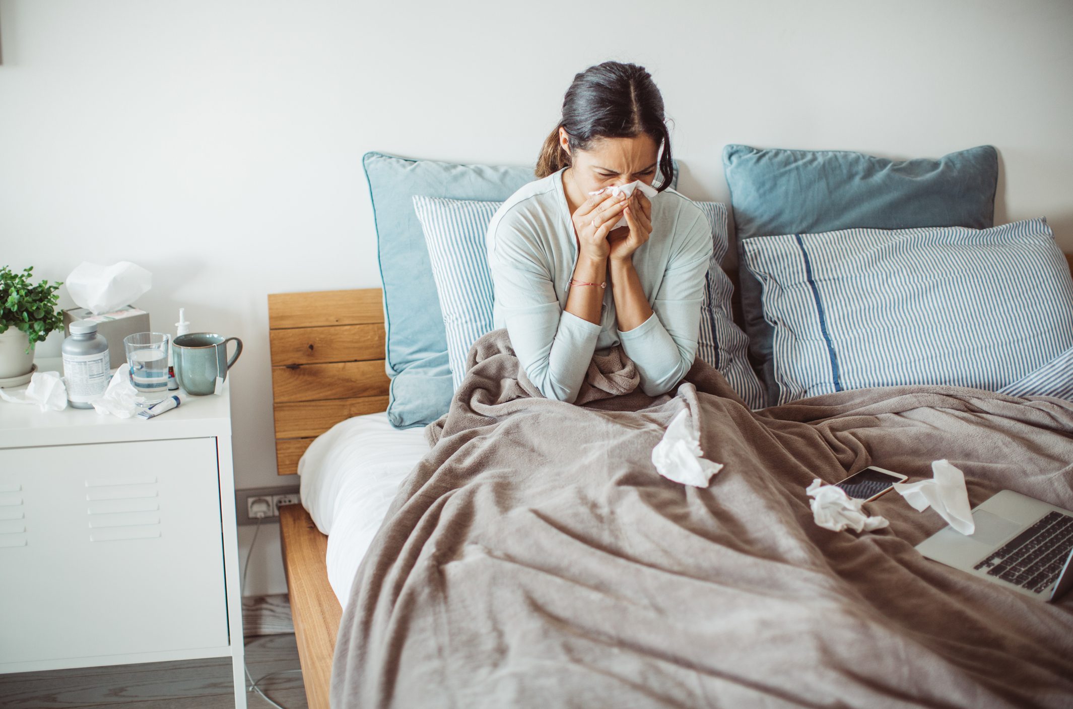 woman sitting in bed blowing nose