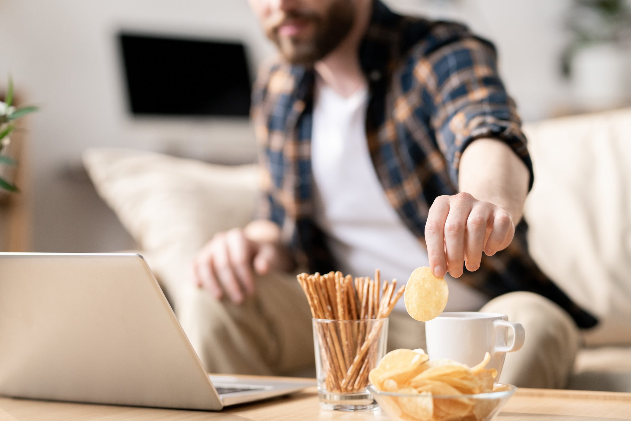 man grabbing snack while working on laptop