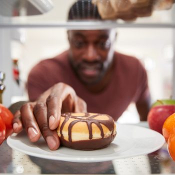 view from inside of refrigerator as man reaches for donut