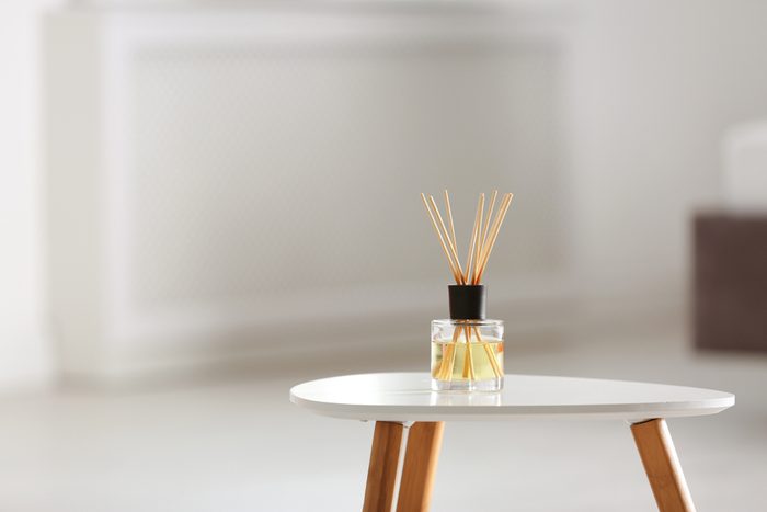 Aromatic reed air freshener on table against blurred background