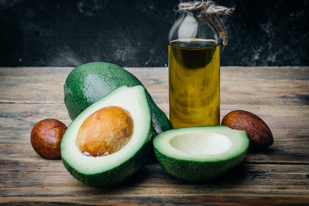 Avocado and avocado oil on a wooden background.