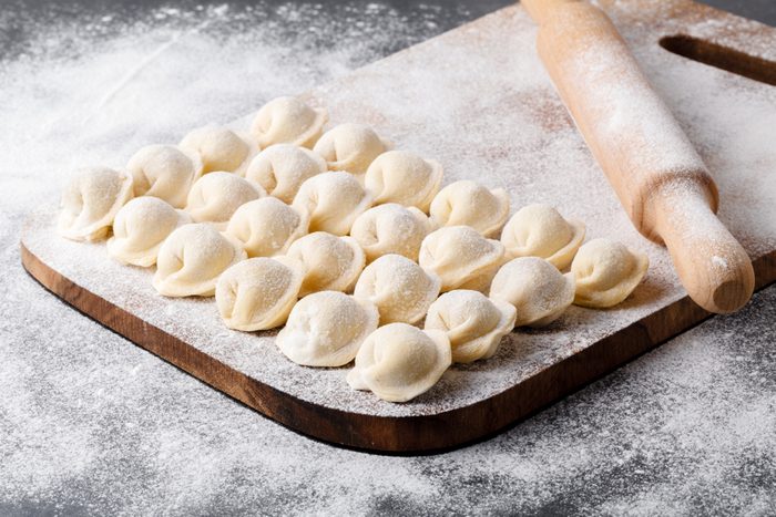 Uncooked Russian pelmeni on a cutting board.