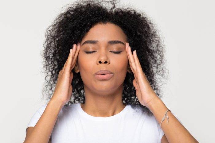 Nervous woman trying to take relaxing, calming breaths while massaging her temples.