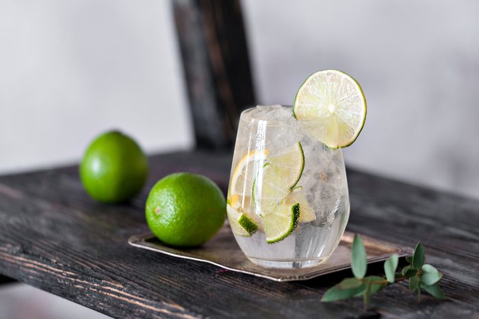 Cold cocktail with lime, lemon, tonic, vodka and ice on vintage shelf.