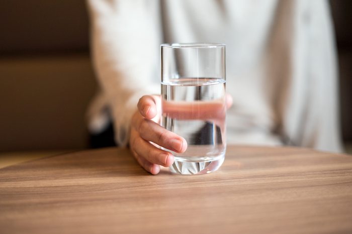 Woman holding a glass of water.